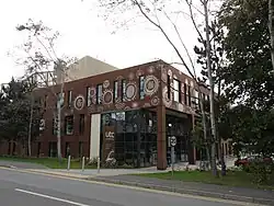 A modern, cuboidal building with rust-brown metal walls decorated with large white cogwheel motifs