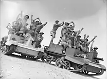 Soldiers standing on two mechanised vehicles in the desert