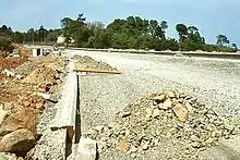 An incomplete road surface leading into trees