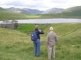 Two walkers looking over the lake with mountains in the background