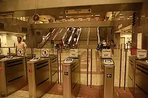 Open indoor area with ticket windows, fare-collection machines and an escalator