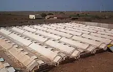 The condenser at Satapar in India consists of eleven ridges. The ridges are trapezoidal in section (top 50 cm, base 200 cm, two sides sloping 30-degree from horizontal, height 100 cm) and each is 20 m long. The ridges are built over gently sloping ground. All the ridges drain into a common pipe at the lower and leading to storage below ground. Water for use is withdrawn by a hand pump. The system was commissioned in early April 2007. Total cost of the installation was Rs 117,000.