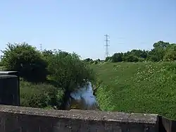 A narrow river with built up grassed banks