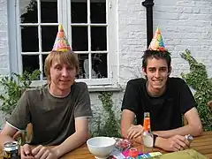 Two people wear party hats at a birthday party.