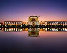 Grâce à son reflet dans un plan d'eau, vue double du palais. Les fenêtres sont éclairées, car la nuit approche.