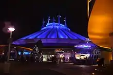 Bâtiment blanc conique éclairé par une lumière bleue.