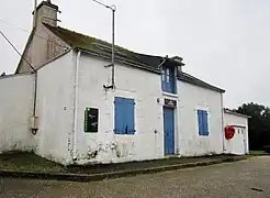 Photographie en couleurs d'une maison éclusière, petit bâtiment aux murs blancs et aux volets bleus.