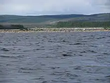 Sur le cours de la rivière Caniapiscau en été, on voit des pierres dans une partie du lit à la surface.