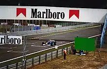 Photo d'une monoplace bleue circulant sur une ligne droite des stands