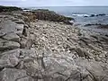 Falaise et estran rocheux côté ouest de la Pointe des Saisies ayant conservé des traces de leur ancienne exploitation comme carrière.