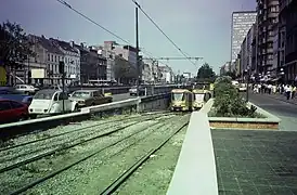 Un tram 18 en direction de  Fort Jaco sort du prémétro sur l'avenue de la Toison d'or et arrive à la place Louise. Il croise un tram 32 barré en direction de Jette avec en arrière-plan la porte de Namur (1985)