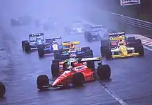 Photo de nombreuses voitures de Formule 1 sur une piste détrempée