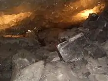 Des cristaux cubiques transparents dans une anfractuosité avec un éclairage jaune les illuminant.