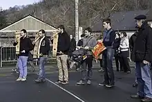 Groupe de musiciens debout, avec un tambour et des instruments à corde.
