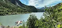 Lac du Chambon (depuis la Cabane au bord du lac). Cette photo montre un panorama ensoleillé depuis la terrasse du café en bord de lac.