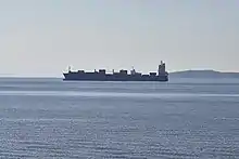 Photographie du golfe Saronique. Au second plan, un cargo de marchandise de profil.