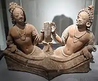 Deux rois nāga émergeant à mi-corps d'un bassin, de part et d'autre de la tige d'un lotus. Vallée du Ghorband. Monastère de Fondukistan, niche D. VIIe&nbsp;siècle. Terre séchée. Musée Guimet, Paris.
