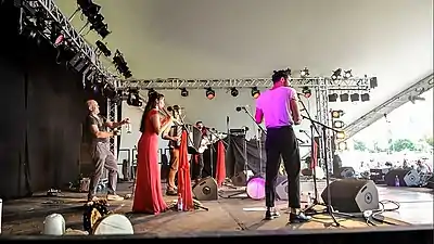 Mark Glanville&nbsp;(en) frappe avec une baguette une bouteille en verre au WOMAD avec le groupe Amaraterra