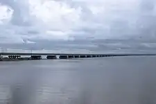 Photographie depuis une rive d'une partie d'un pont surbaissé enjambant une étendue d'eau.