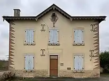 La façade principale de couleur beige d'un ancien bureau de poste.