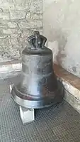 L'ancienne cloche de l'église exposée sous le porche.