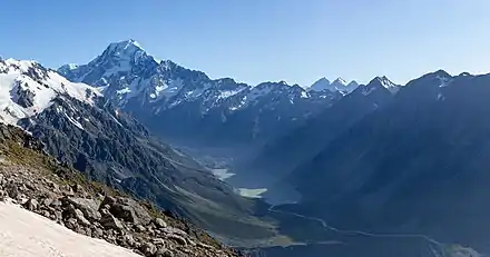 Une montagne pointue et neigeuse couronne une vaste vallée.