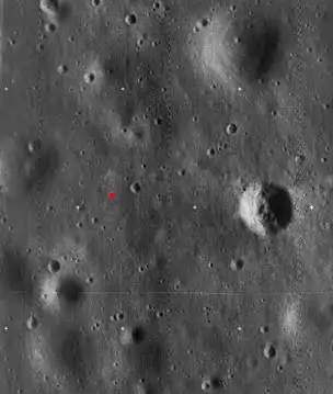 Image haute résolution de Lunar Orbiter 5, recadrée pour montrer le site d'atterrissage d'Apollo 11. Le site d'atterrissage est indiqué par un point rouge. Le cratère proéminent à droite est appelé cratère Ouest et mesure environ 190&nbsp;m de diamètre.