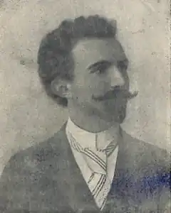 Portrait en noir et blanc d'un homme barbu et à la moustache proéminente portant un costume et une cravateModèle:Sngn.