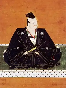 La daimyō Azai Nagamasa vêtu de noir et assis en tailleur.