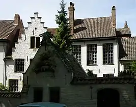 Les maisons no&nbsp;10 (à droite, début XIXe&nbsp;siècle) et no&nbsp;12 (à gauche, au pignon à gradins, XVIIe&nbsp;siècle). À l’avant-plan, apparaissant sombre sur la photo car à l’ombre des peupliers, le pigeonnier.