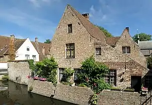 Façade arrière de la maison no&nbsp;9, dont on distingue bien les différents corps de bâtiment : le principal (au centre de la photo) et celui à droite sont du XVIe, XVIIe et XVIIIe&nbsp;siècles ; les appentis sont de date plus récente. À l’avant-plan, l’étroit canal qui traverse le béguinage. La façade-pignon blanche à gauche appartient au no&nbsp;46.