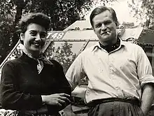 Photographie noir et blanc d'une femme et d'un homme devant une voiture.
