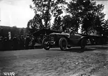 Photo d'une voiture en course avec, hors de la piste, des spectateurs.