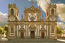 Photographie en couleurs. Vue de la façade de l'église devant un ciel nuageux.