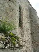 Mur de l'église présentant des ouvertures étroites typiques des églises du XIIIe&nbsp;siècle.