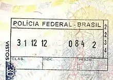 Photographie en couleurs, représentant un tampon des services de l'immigration brésilienne, sur un passeport.