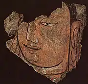 Détail d'une tête du Bouddha 21B. Registre haut du sanctuaire B en bois et enduits peints, vallée de la Keriya. Début du IIIe&nbsp;siècle. Musée provincial, Ürümqi.