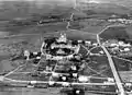 Vue aérienne d'une colline avec des bâtiments aux alentours, avec au sommet deux édifices religieux.