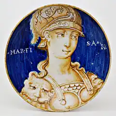 Plat peint en bicolore bleu et ocre à buste féminin orné d'une armure et d'un casque à plumes ; sur le fond bleu le mot « Marfisa » ; typologie des « Belles Femmes », Casteldurante, première moitié du XVIe&nbsp;siècle.
