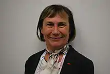 Photo en buste d'une femme souriante portant une veste noire.