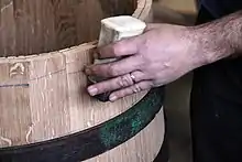 Cerclage d'un tonneau à l'aide d'une chasse, après la mise en rose des douelles.