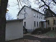 Une annexe de bâtiment de deux étages et demie de plan rectangulaire, revêtue de briques de couleur beige.