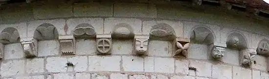 Photographie en couleurs montrant le détail des sculptures d'une corniche en pierre.