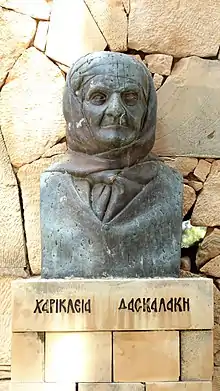 Buste en bronze sombre d'une femme âgée ayant un fichu enroulé autour de la tête.