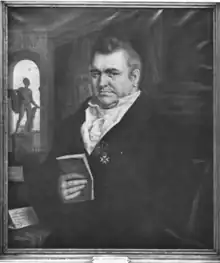 Photographie noir et blanc d'un tableau montrant un homme assis, corpulent, tenant dans sa main un livre.