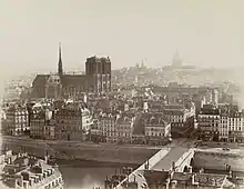 Sur cette photographie, prise vers 1865 depuis la tour Saint-Jacques, une grande partie du quai de la Corse est visible, au-delà du grand-bras de la Seine, de part et d'autre du pont Notre-Dame. Il est encore bordé de maisons anciennes sur cette section. Du fait des grands travaux haussmanniens, particulièrement importants sur l'île de la Cité, ces demeures vont bientôt disparaître et être remplacées, à gauche du pont, par le nouvel Hôtel-Dieu, et à droite par le marché aux fleurs.
