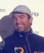 Portrait, coiffé d'une casquette, souriant.