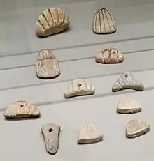 Jetons en argile aux formes diverses, incisés de motifs linéaires et de signes ronds.