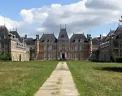 Grande bâtisse, de style Louis XIII, briques rouges, toit d'ardoise, trois étages, vue de loin, depuis le parc. Vue de la façade nord-ouest.