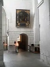 Photographie en couleurs d'un passage voûté dans un mur.